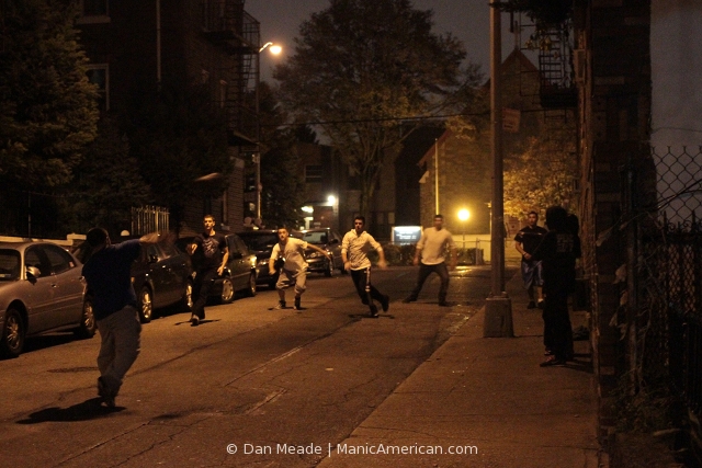 A group of friends play football in a city street.