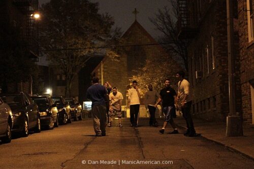 A group of friends play football in a city street.