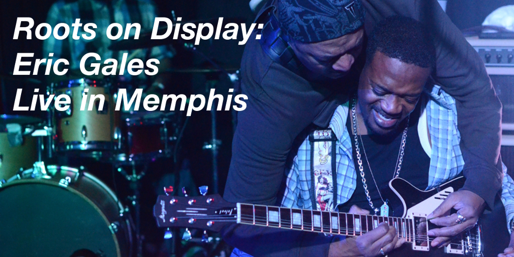 Summary graphic: One man, Eric Gales, plays a guitar while seated. Another man, his brother, stands behind him, reaches over his shoulders, and plays the guitar as well.