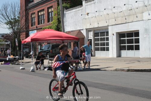 A child with face paint rides his bike.