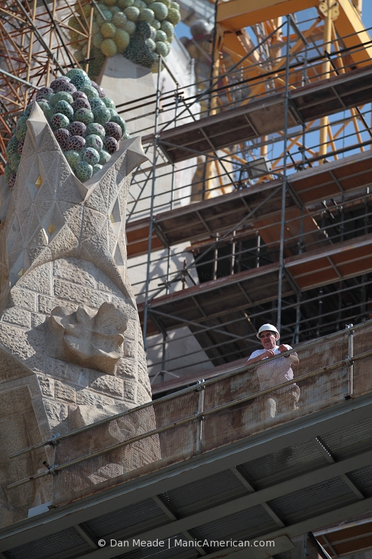 A construction worker standing before a great deal of scaffolding examines work being done on the Basilica de la Sagrada Familia.