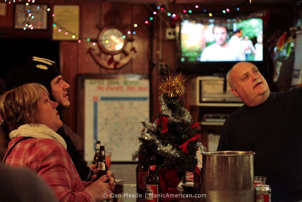 Nothing seperates this bartender from his patrons, except for a Christmas tree.