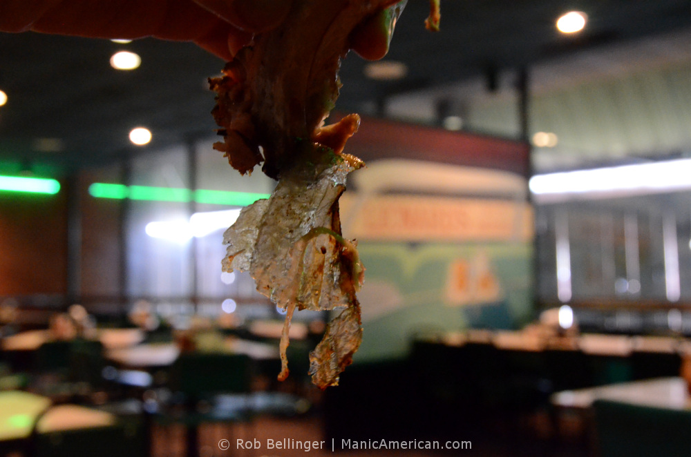A view of the translucent membrane taken off a smoked rack of ribs, with the restaurant's dining room in the background
