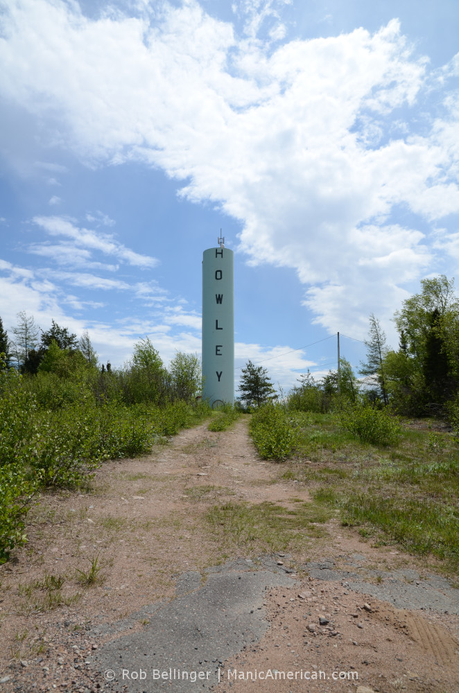 A skinny water tower with the name of the town of Howley, Newfoundland sits under an open sky.