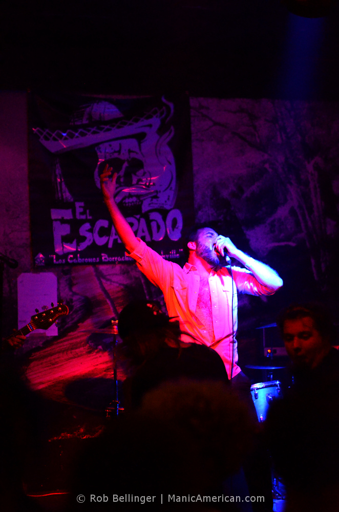 the singer of the band el escapado raising his hand as he sings