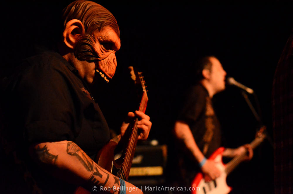 a guitarist wearing an alien ape mask