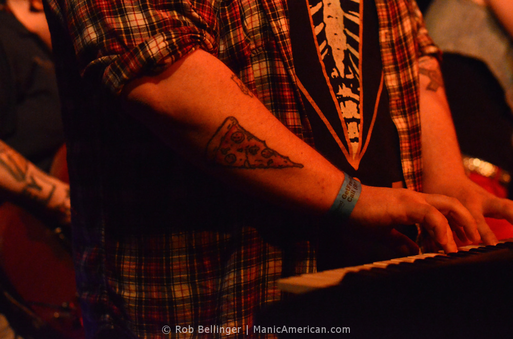 a pizza slice tattoo on the forearm of a keyboard player