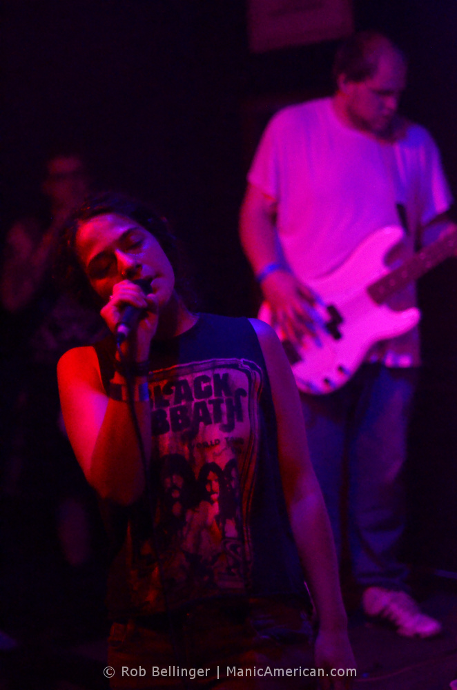 female singer of bombflower wearing a black sabbath t-shirt with a bass player in the background