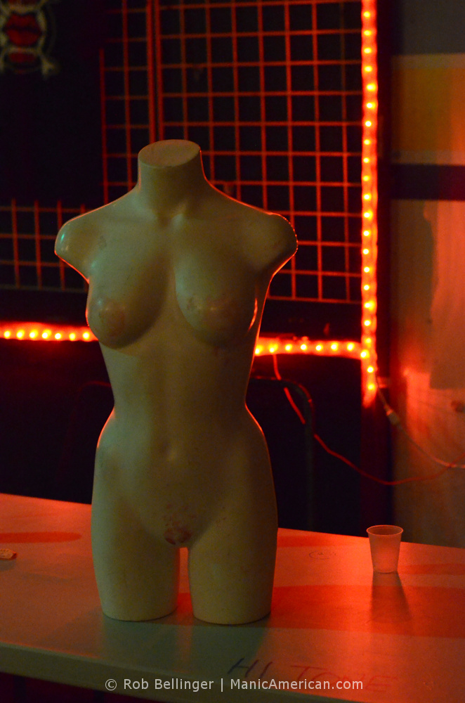 a nude female mannequin on a table with red lights in the background