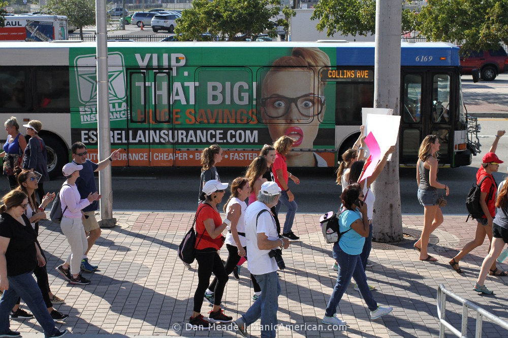 Marchers pass a tounge-in-cheeck bus ad