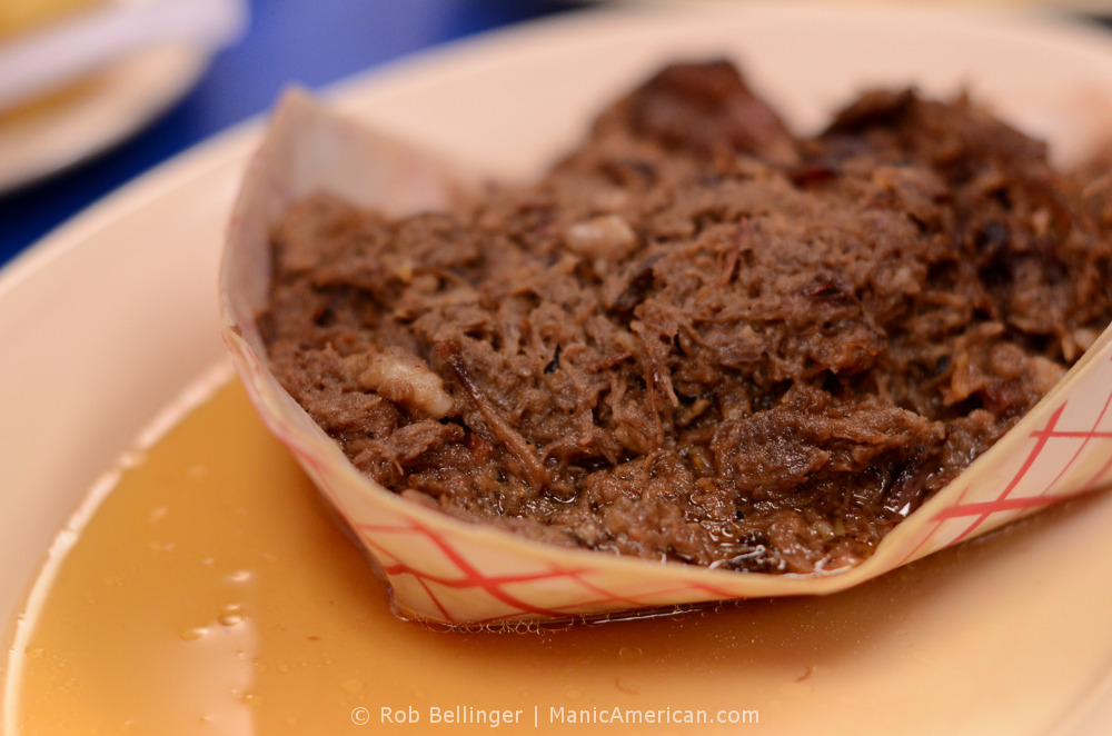 Kentucky barbecue: a paper tray of smoked, pulled lamb meat leaks grease onto a plate