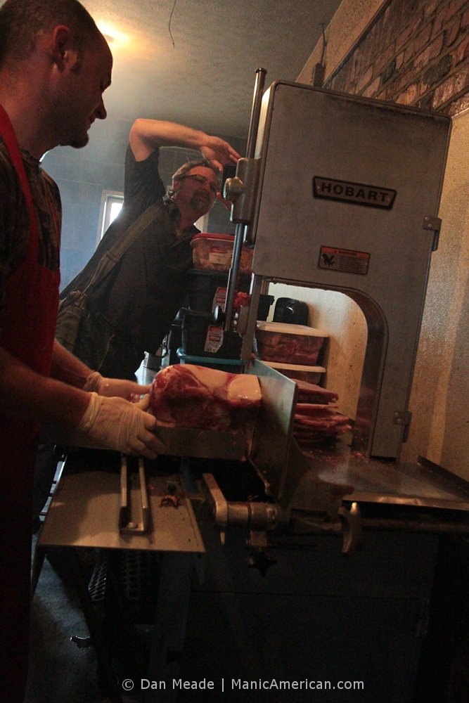 Wes Berry photographs a pork shoulder being sliced.