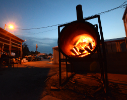 In the woodlot of a Kentucky barbecue restaurant at night, logs burn in a furnace