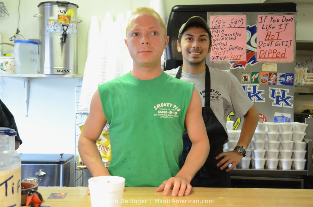 Two employees stand at the front counter of the Smokey Pig Kentucky barbecue restaurant during lunch rush