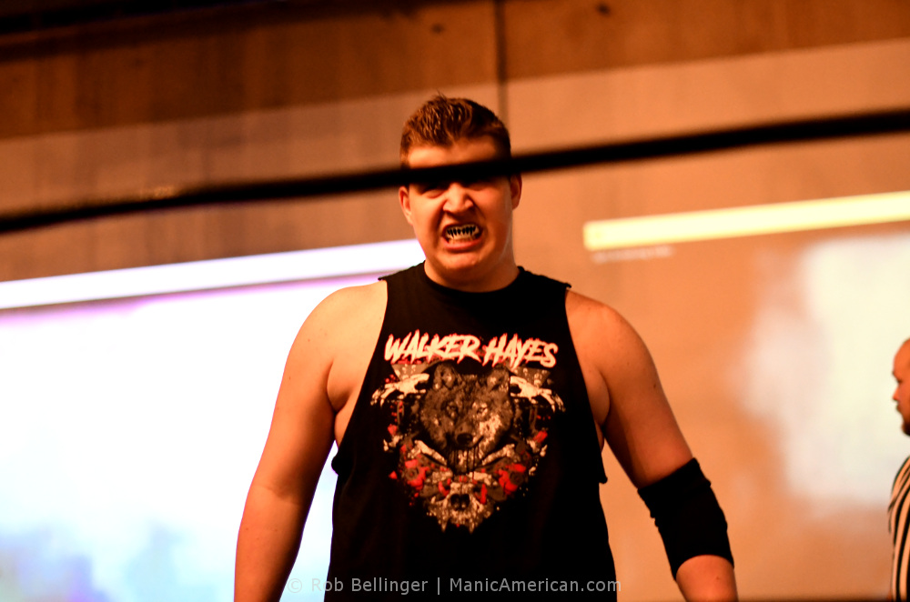 With the top rope blocking the view of his eyes, Walker Hayes steps into the ring wearing a shirt showing his name in heavy metal font and a wolf surrounded by bloody bones.