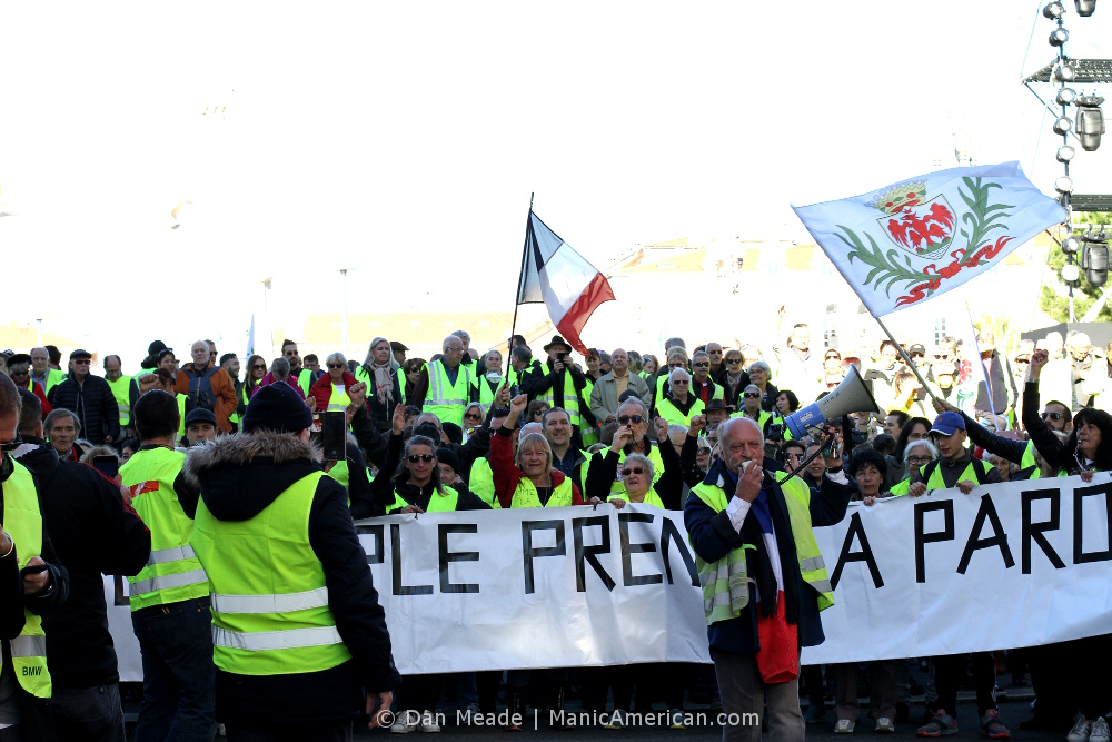 A mass of gilets jaunes protestors with flags and banner.