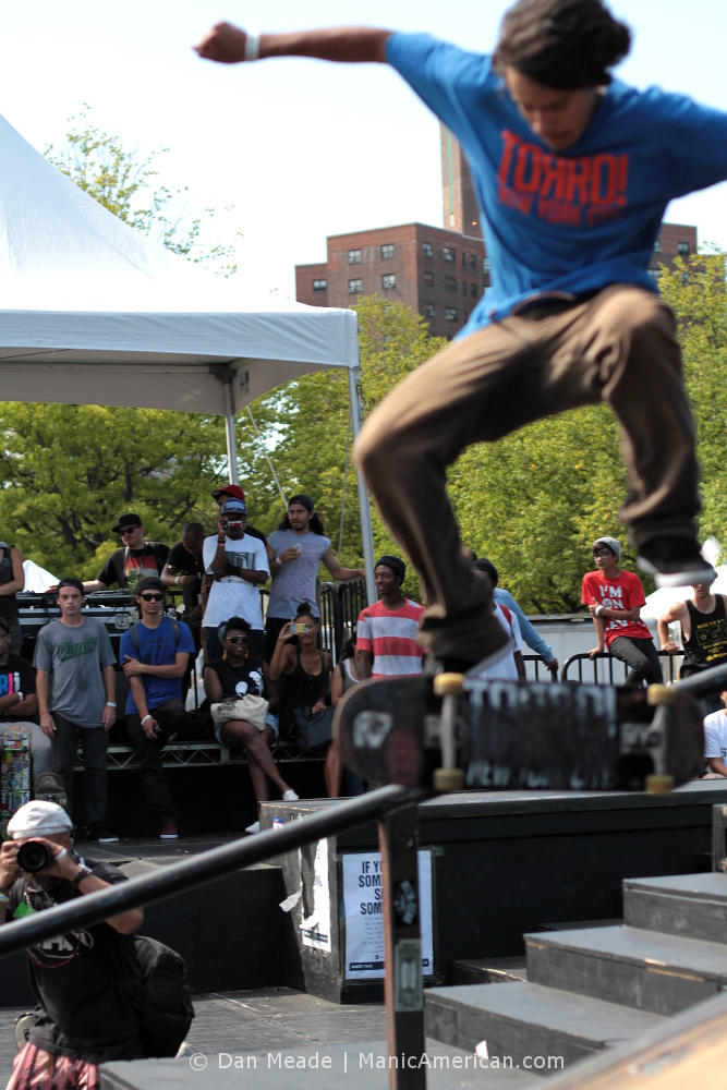 A skater performs a trick before a crowd.