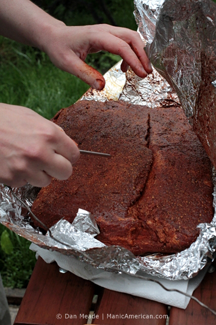 A meat thermometer is inserted into a raw brisket.