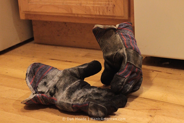 Charcoal covered gloves lie on a floor.