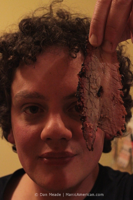 The chef holds up a slice of brisket.