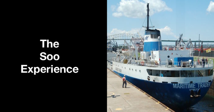 Summary graphic: A ship, the Maritime Trader, passes through the Soo Locks while a dockworker looks on.