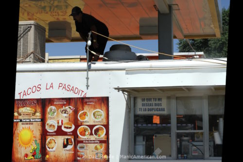 A worker inspects a HVAC unit atop a food truck.