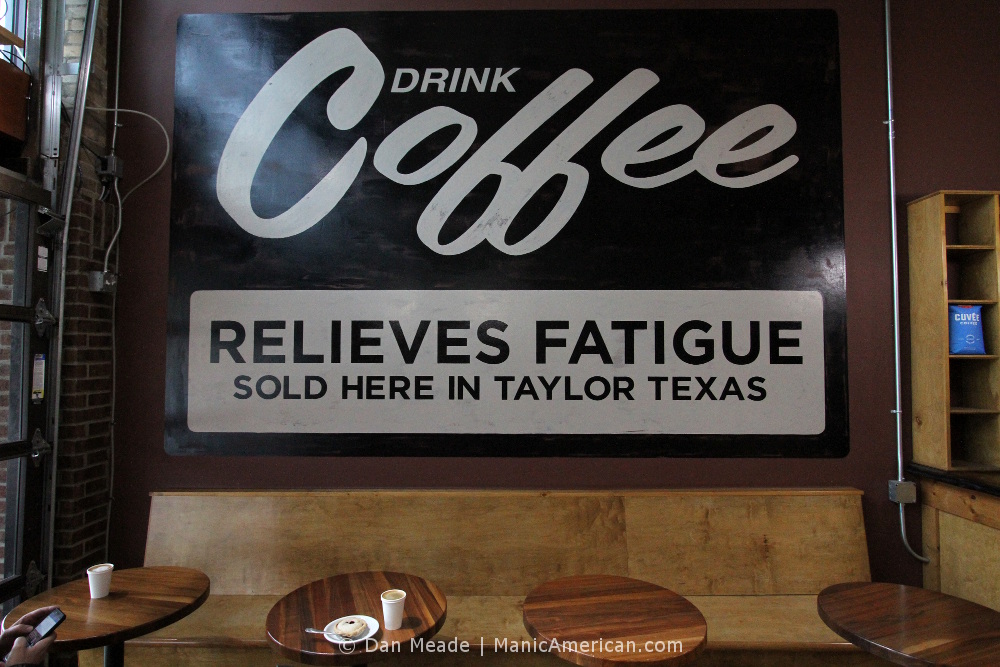 A sign declares, "DRINK COFFEE - RELIEVES FATIGUE"