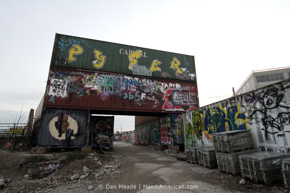 Graffiti-covered shipping contains in the shape of an arched medieval gate leading into Munich’s Bahnwarter Thiel.