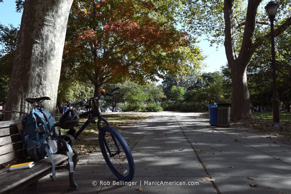 A bike sits against a park bench