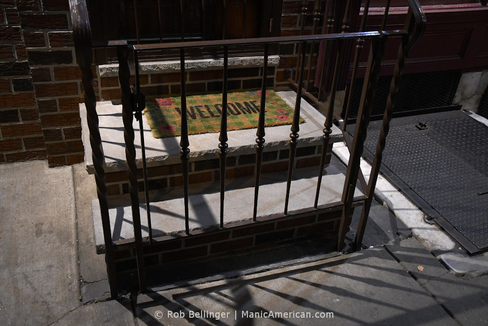 a welcome mat on a small stoop surrounded by an iron fence