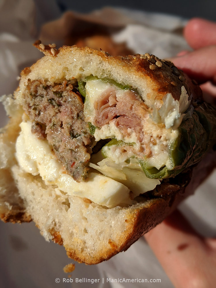 a cross-section of a hoagie containing meatballs, cheeses, and a long hot pepper stuffed with cheese and salami