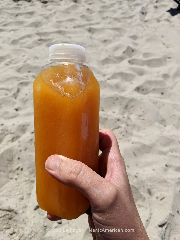 a plastic bottle containing a frozen, brown alcholic beverage, known as a nutcracker, on rockaway beach