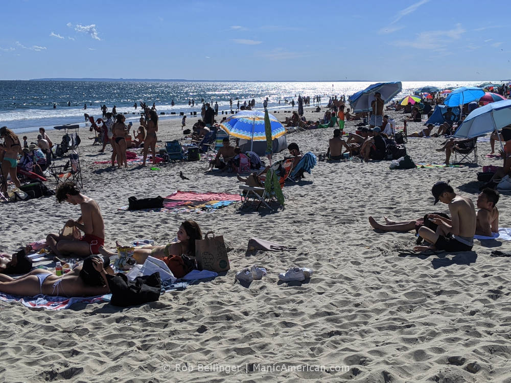 a crowd of beachgoers in summer sun at rockaway beach