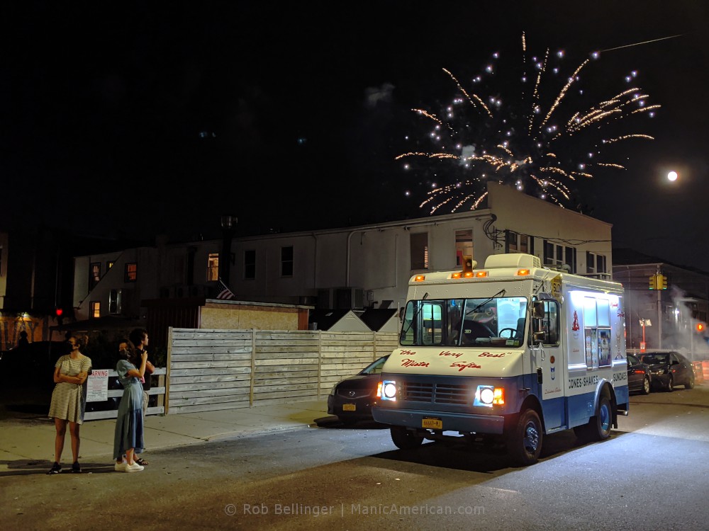 fireworks explode over an ice cream truck in rockaway beach as three tourists take photos