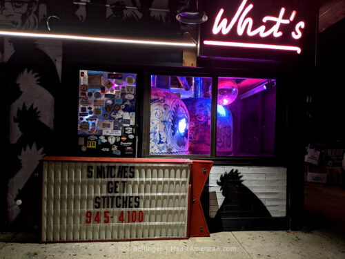 two brick pizza ovens inside a restaurant with a neon sign that says "whit's," with a hand-lettered sign stating "snithces get stitches," at whit's end restaurant in rockaway beach