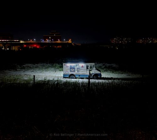a lone ice cream truck on rockaway beach at night with subway station in background