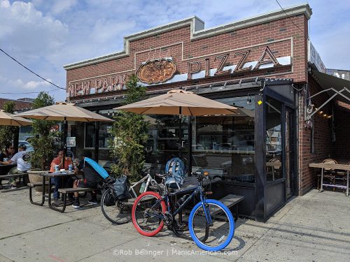 the exterior of new park pizza in howard beach queens showing picnic tables and two bikes